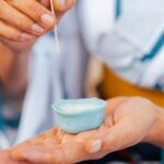 A pair of hands shaping traditional Japanese wagashi, forming a quiet blue sweet with focused attention.