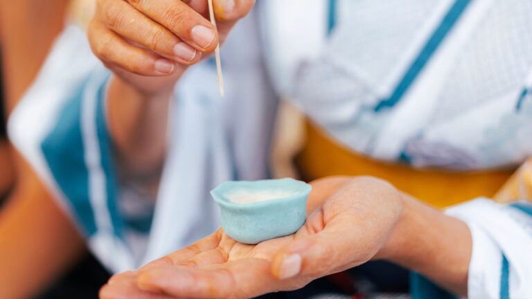 A pair of hands shaping traditional Japanese wagashi, forming a quiet blue sweet with focused attention.